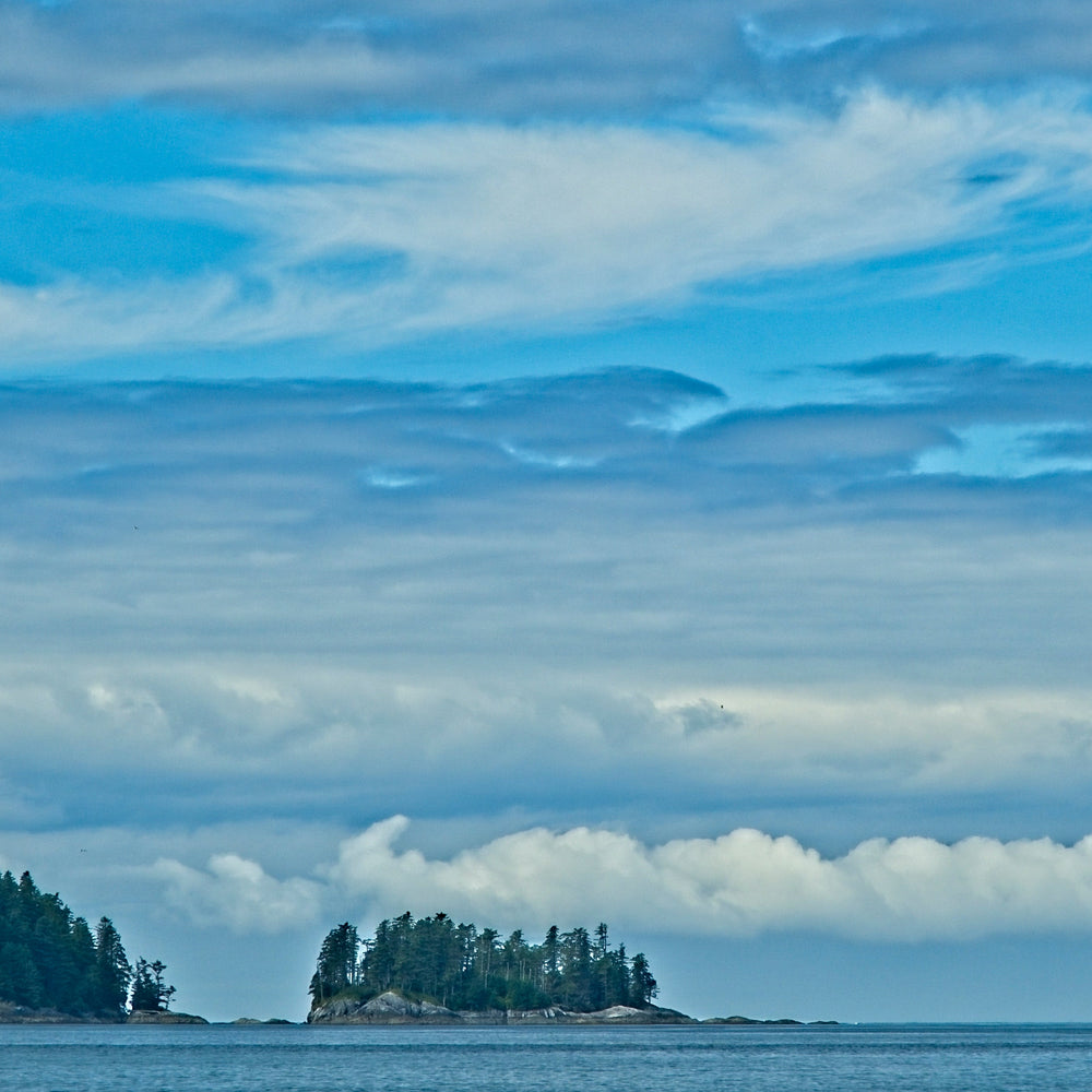 Island in a body of water with a blue sky and clouds