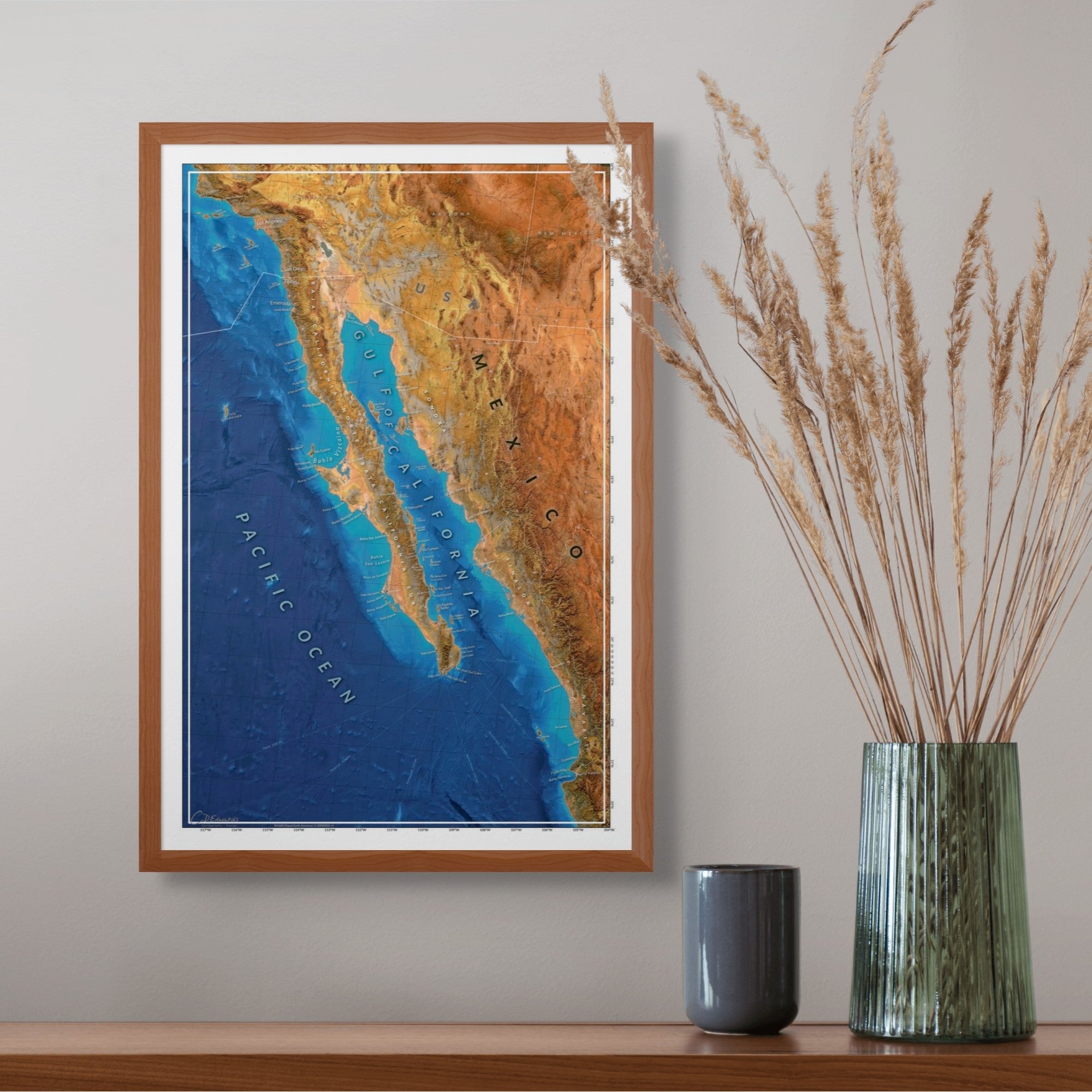 Framed topographic map of Baja Mexico on a wall with decorative vases below.