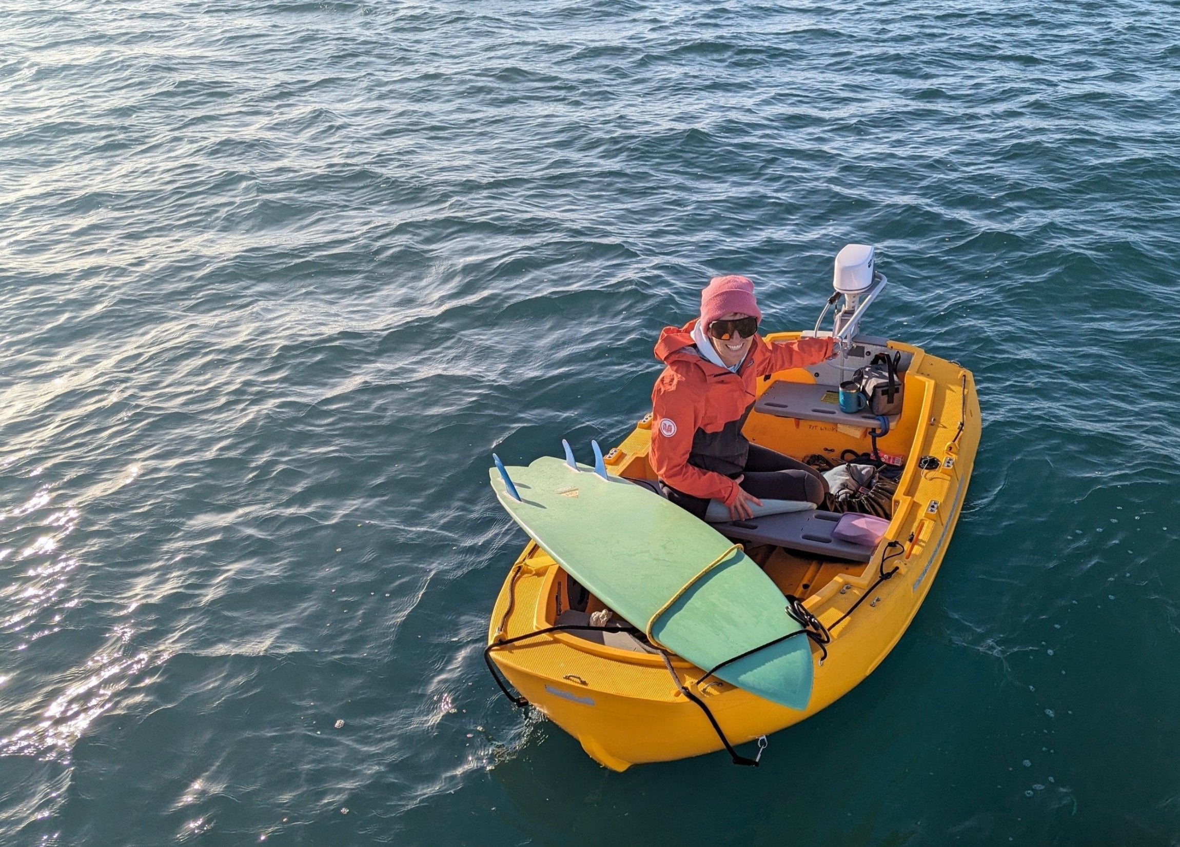 Person in a small yellow boat on the water with equipment.