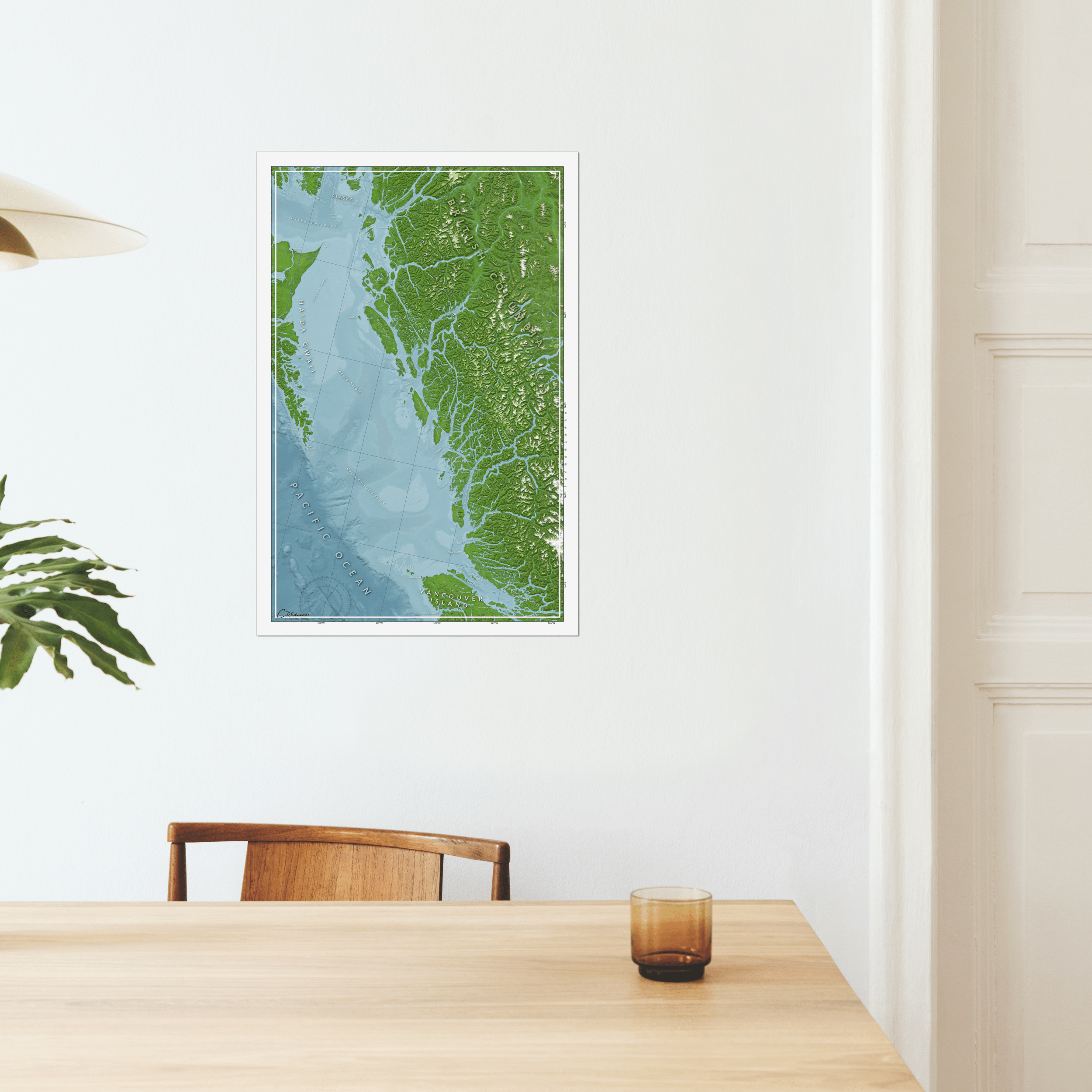 A kitchen table with a map of the Great Bear Rainforest hung on the wall above a chair